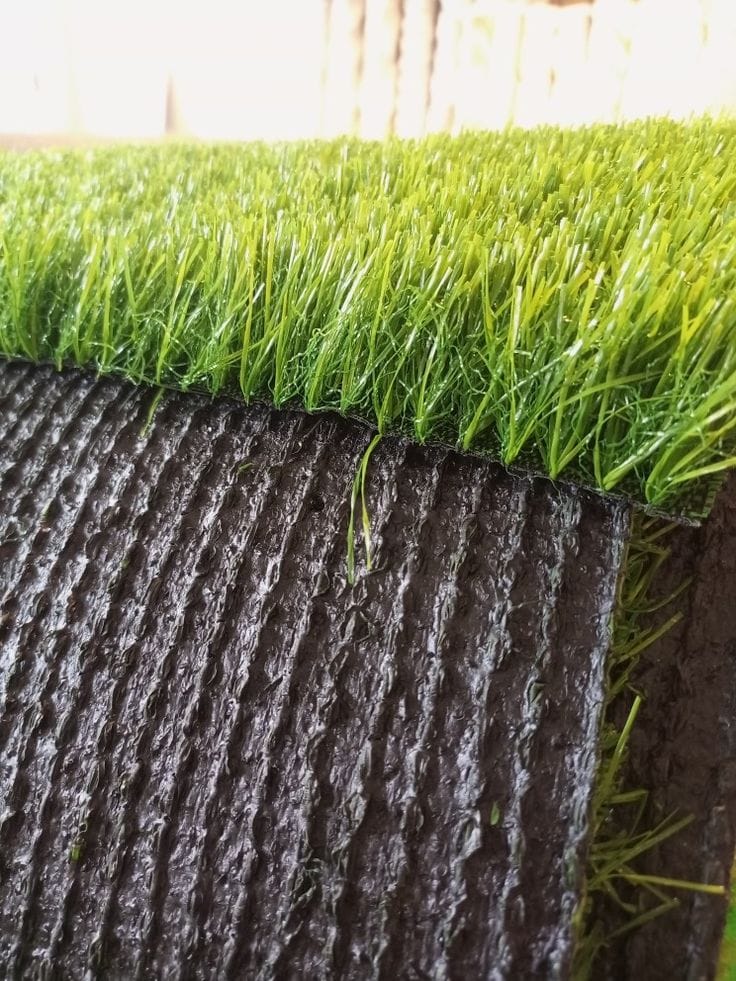 Detail of artificial grass along a step riser, fibres brushed in one direction showing the lay.