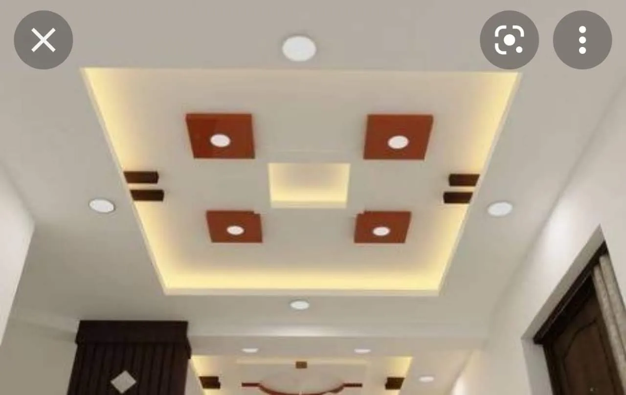 Ceiling with terracotta-toned square accents and warm concealed cove lighting beside a doorway.