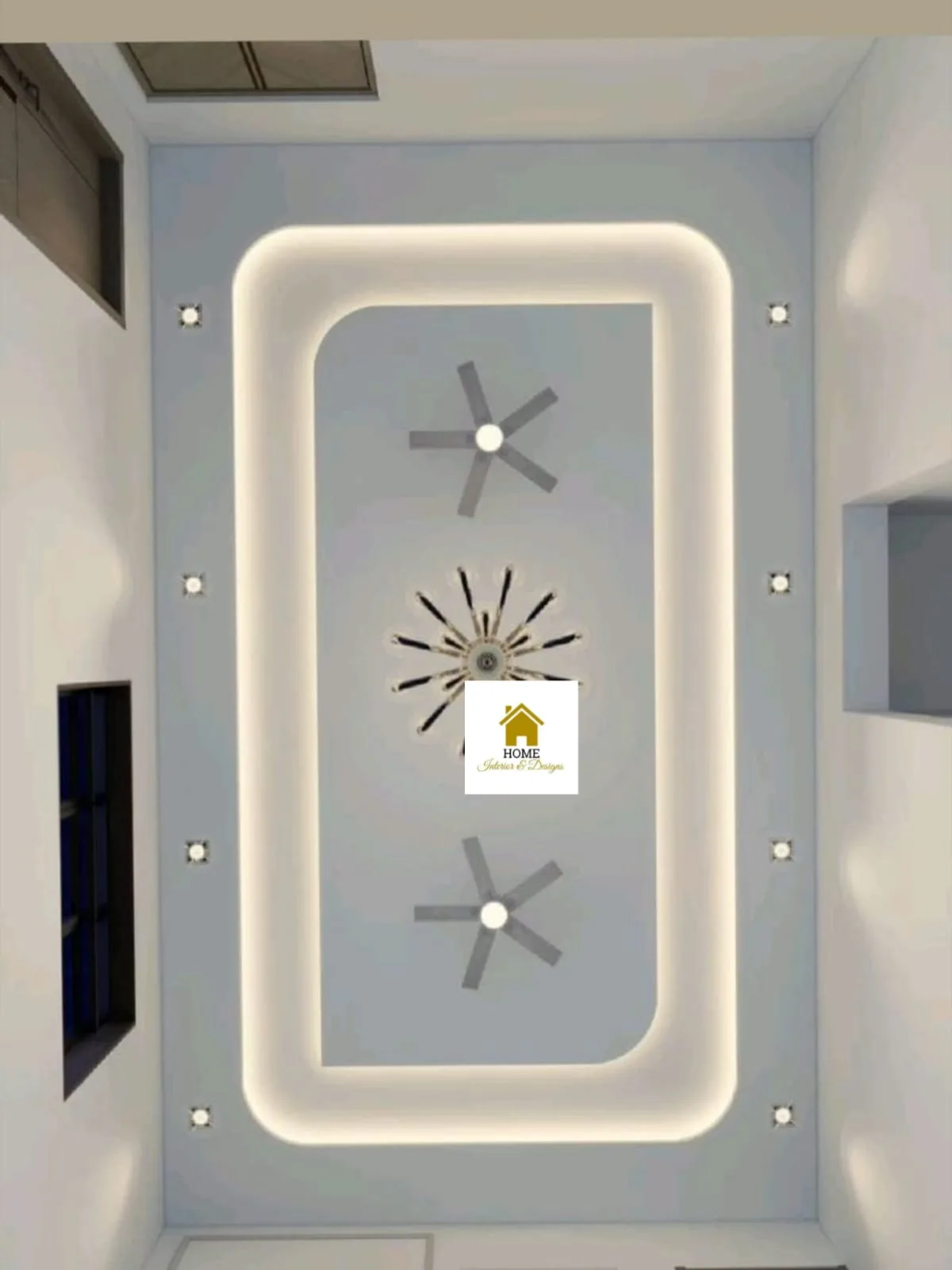 Portrait view of a rounded false ceiling tray washed by continuous cove light, with two ceiling fans, a starburst chandelier and recessed pin lights.